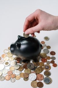 black piggy bank surrounded with coins